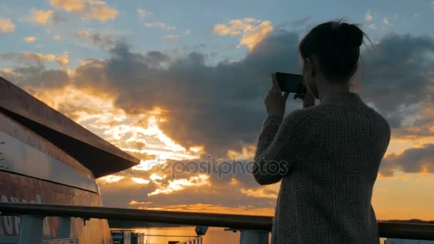 Kvinna siluett att ta foto av solnedgången med smartphone på däck på kryssningsfartyg — Stockvideo