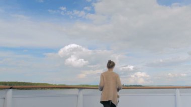 Cruise gemi güverte üzerinde duran ve nehir ve manzara bakarak genç kadın