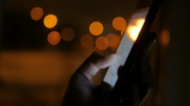 Geceleri dikey siyah akıllı telefon kullanan bir kadın