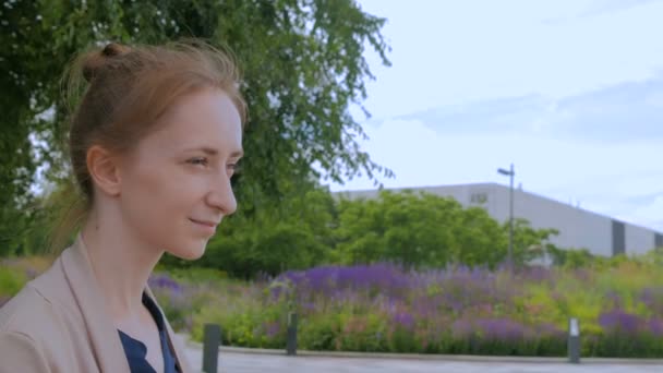 Молодая женщина осматривается в парке — стоковое видео