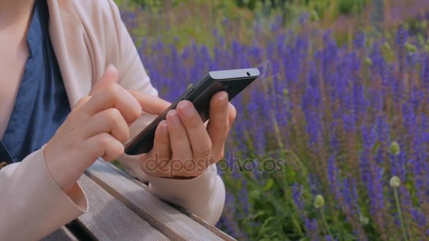 Kvinna som använder smartphone i parken — Stockvideo