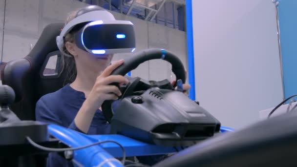 Mujer joven usando auriculares de realidad virtual y jugando en simulador de conducción de coche — Vídeos de Stock