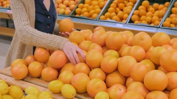 Женщина покупает свежие грейпфруты в продуктовом магазине — стоковое видео