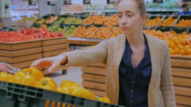 Frau kauft frische orangefarbene Paprika im Supermarkt — Stockvideo