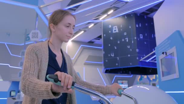 Jeune femme utilisant une machine de simulation de vélo interactive — Video