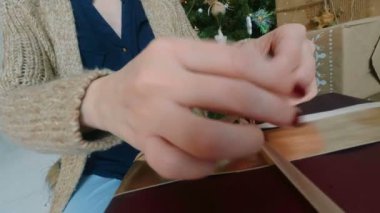 Kadın Noel hediye kutusuna kurdele sarar.