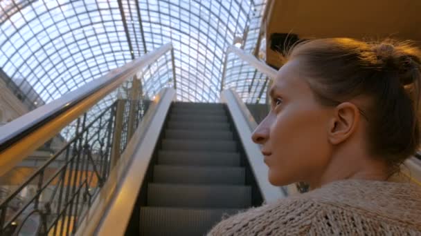 若い女性はエスカレーターで移動し、モールで見て回る — ストック動画