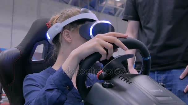 Sanal gerçeklik kulaklığı kullanan ve araba sürücüsü simülatöründe oynayan genç bir kadın. — Stok video