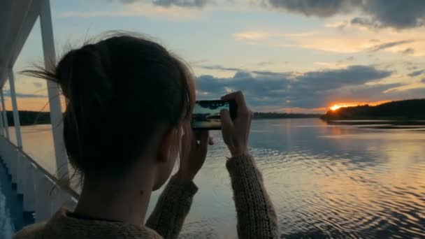 Silhueta mulher tirando foto do pôr do sol com smartphone no convés do navio de cruzeiro — Vídeo de Stock