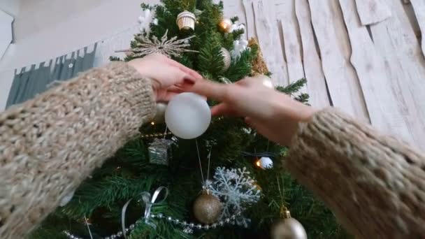 Женщина украшает елку игрушками — стоковое видео