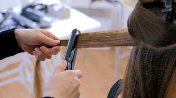 Peluquería usando plancha en el pelo largo del cliente en la peluquería — Foto de Stock