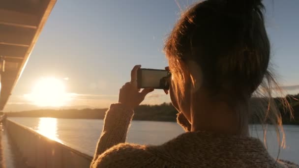 Жінка силует фотографує захід сонця зі смартфоном на палубі круїзного корабля — стокове відео