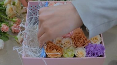 Çiçekçide çiçeklerle hediye kutusu yapan profesyonel bir çiçekçi.