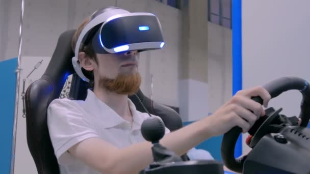 Hombre joven usando auriculares de realidad virtual y jugando en simulador de conducción de coche — Vídeos de Stock