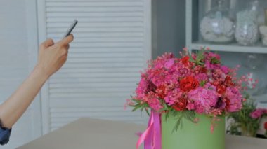 Akıllı telefonlu güzel bir buketin fotoğrafını çeken bir kadın..