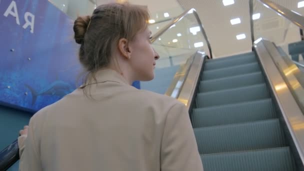 Junge Frau bewegt sich auf Rolltreppe und schaut sich in Einkaufszentrum um — Stockvideo