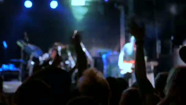 Silhuetas de pessoas festejando e batendo palmas em concerto de rock em frente ao palco — Vídeo de Stock