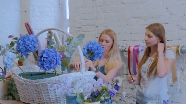 Duas floristas mulheres fazendo grande cesta floral com flores na loja de flores — Vídeo de Stock