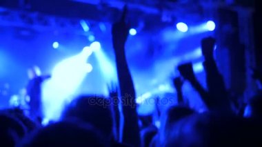 Rock konserinde sahne önünde parti insan siluetleri.