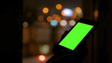 Yeşil ekranlı akıllı telefona bakan kadın