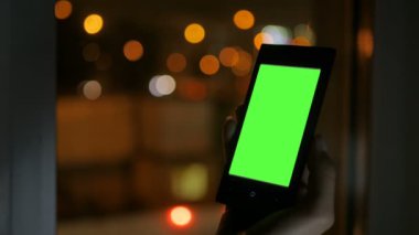 Yeşil ekranlı akıllı telefona bakan kadın