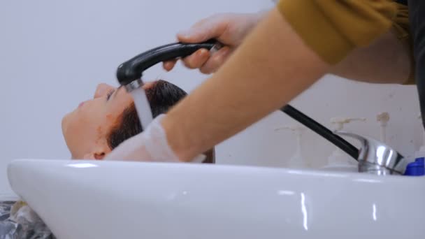 Парикмахер моет волосы клиентке — стоковое видео
