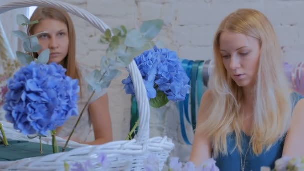 Två kvinnor blomsterhandlare gör stora blommor korg med blommor i blomsteraffär — Stockvideo