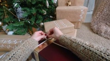 Kadın Noel hediye kutusuna kurdele sarar.