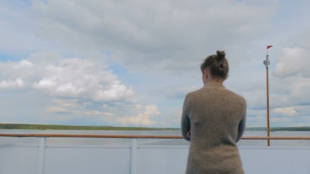 Junge Frau steht an Deck eines Kreuzfahrtschiffes und blickt auf Fluss und Landschaft — Stockvideo