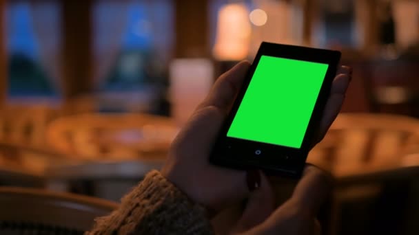 Frau schaut in Café auf Smartphone mit grünem Bildschirm — Stockvideo