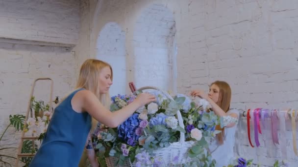 Dos floristas mujeres haciendo gran cesta floral con flores en la tienda de flores — Vídeo de stock