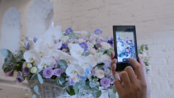 Woman taking photo of large floral basket with flowers with smartphone. — Stock Video