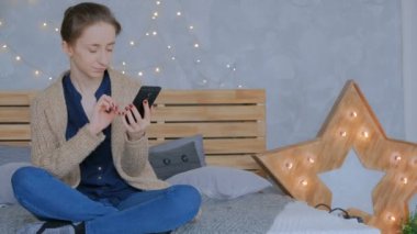 Evde dikey siyah akıllı telefon kullanan bir kadın