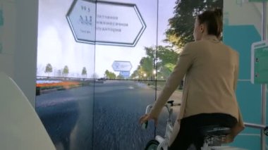 Etkileşimli bisiklet simülatörü kullanan genç bir kadın