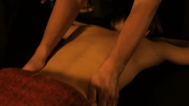 Masör, kaplıca merkezinde bayan müşteriye sırt masajı yapıyor.