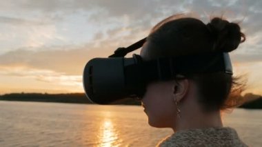 Sanal gerçeklik gözlükle cruise gemi güvertesinde günbatımında kadın