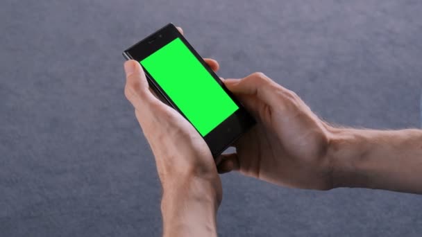 Мужчина смотрит на смартфон с зеленым экраном — стоковое видео