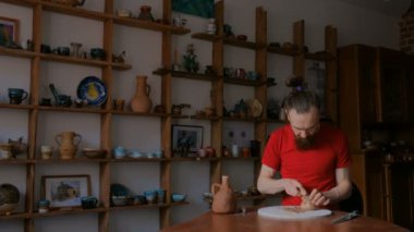 Profesyonel çömlekçi, çömlek atölyesinde özel bir aletle kuru kil bardağı şekillendiriyor.
