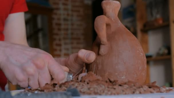 Professional potter shaping dry clay jar with special tool in pottery workshop — Stock Video