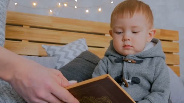 Молода мама і її син читають книгу вдома — стокове відео