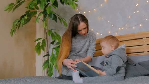 Jovem mãe e seu filho bebê lendo livro em casa — Vídeo de Stock