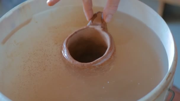 Горшечник, погружающий глиняную чашу в воду — стоковое видео