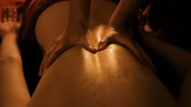 Masör, kaplıca merkezinde bayan müşteriye sırt masajı yapıyor.