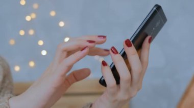 Evde dikey siyah akıllı telefon kullanan bir kadın