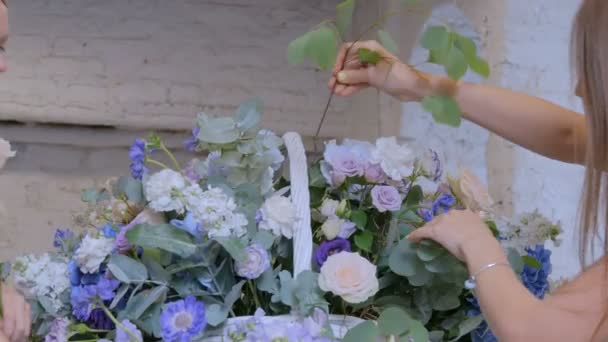 Zwei Floristinnen basteln im Blumenladen einen großen Blumenkorb mit Blumen — Stockvideo