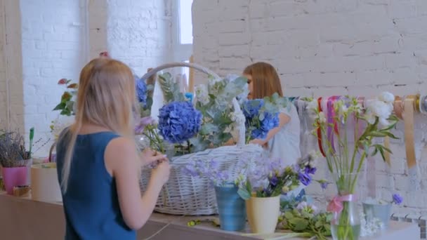 Duas floristas mulheres fazendo grande cesta floral com flores na loja de flores — Vídeo de Stock