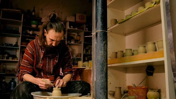Professional potter shaping mug with special tool in pottery workshop