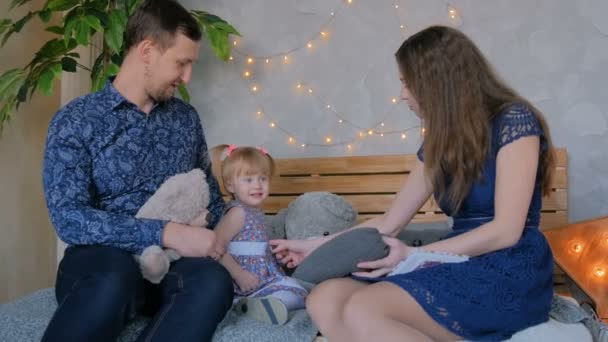 Счастливые молодые родители и их маленькая дочь играют в игрушки — стоковое видео