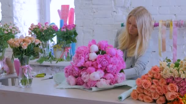 Florist wraps blommor i presentpapper på blomsteraffär — Stockvideo