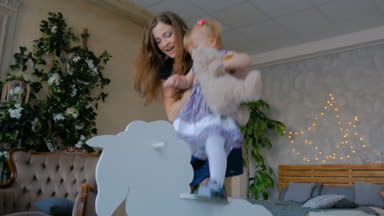 Küçük kız tahta sallanan atta oynuyor.